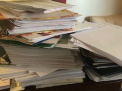 An untidy pile of documents and folders on a desk