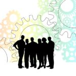 People in a business surrounded by work gears depicting processes and systems - How to be a successful small business owner