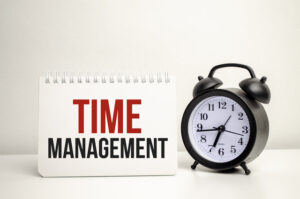 Time management words on a white notebook and clock 