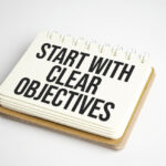 Business concept. Notebook with text START WITH CLEAR OBJECTIVES on sheet of white paper - Define Business Objectives