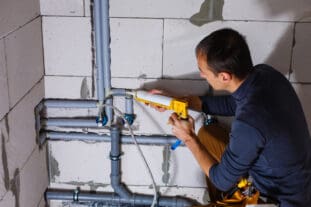 Male Plumber repairs pipes in the toilet - How to Create Financial Projections for a Business Plan