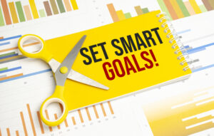 A notepad with the text set SMART goals-pen- reports - How to Use SMART Criteria to Set Objectives