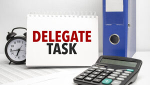 delegate task words on white notebook and calculator, black vintage alarm clock and blue paper folder - How to Survive in Small Business