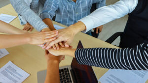 Ggroup-of-business-people-placing-hand-over-hand-to-portray-teamwork- Best Practices Hiring Process