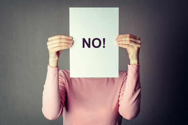 woman covering face behind a white paper sheet with insciption word No - What are the Best Ways to Manage Stress Like a Pro