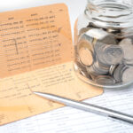 pen on account book bank with coins in glass jar - How to Improve Cash Flow in a Small Business