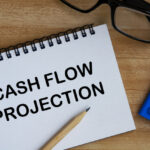 cash flow projection text on notepad with calculator, pencil and glasses background-what is cash flow in business