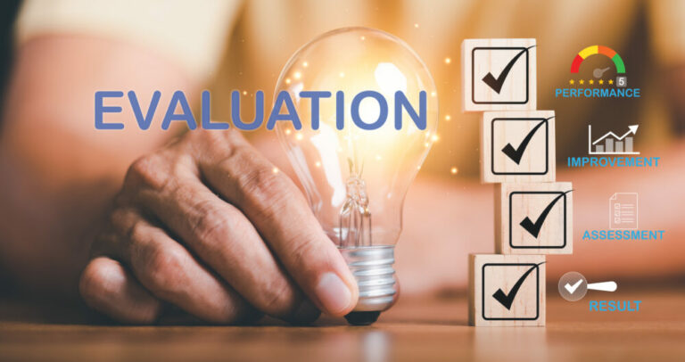 male-hand-holding-light-bulb-beside-wooden-block-result-of-performance-evaluation-on-table - How to Evaluate Small Business Perfomance